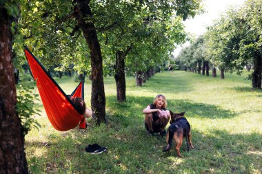 Mutlu gülümseyen kadın ve oğlu yeşil çimlerde hamak, mutlu bir aile ve bir köpek..