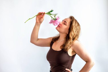 Beyaz arka planda pembe şakayıklı, gülümseyen genç bir kadının güzel portresi.