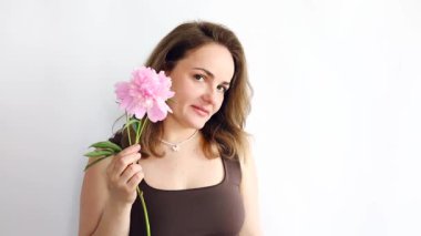 Beyaz arka planda pembe şakayıklı, gülümseyen genç bir kadının güzel portresi.
