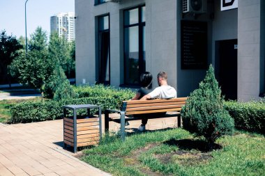 Genç çift şehirde bir bankta oturuyor. Arka plan