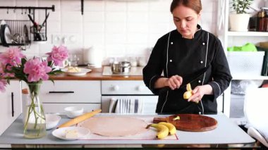 Siyah üniformalı genç bir kadın şef mutfakta muzlu turta hazırlıyor..