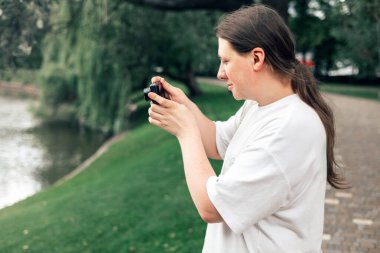 Elinde kamera olan ve dışarıda fotoğraf çeken genç bir çocuk. Hobi ya da kariyer. Kameralı acemi fotoğrafçı. 