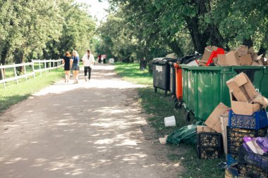 Bir kaç çöp tenekesi ağaçların üzerinde duruyordu.
