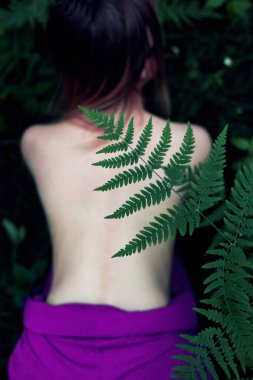 Eğrelti yaprağı kucaklayan hippi kadın. Ormanda çıplak bir kadın..