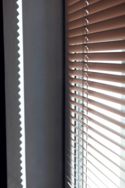 Pencereden gelen güneş ışığı Venedik panjurlarından geliyor.