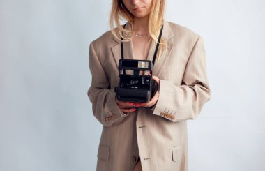 Beyaz arka planda polaroid fotoğraf makinesi tutan genç bir kız.. 