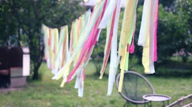 Renkli asılı kurdelelerin güneş ışığında rüzgarda sallanmasının sonu. Yaz gündönümünde birçok kurdeleden dekoratif soyut kompozisyon park içinde.