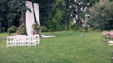 Sandalyeli çiçeklerden yapılmış bir düğün töreni için güzel kemer. Beyaz ahşap sandalyeler, düğün töreni için evin dışına kurulmuş..