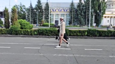 Yaz günü rehber köpekle parkta yürüyen genç adamın yan görüntüsü..