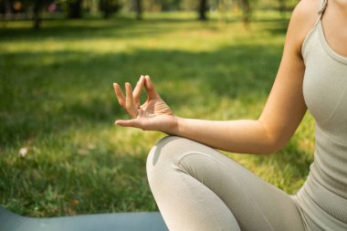 Parkta yoga yapan genç bir kadın. Sağlıklı yaşam tarzı ve rahatlama kavramı.