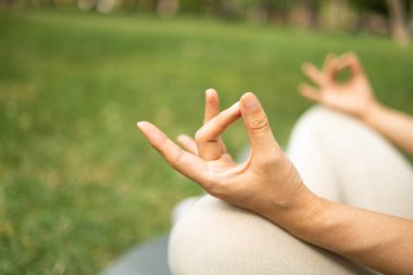 Parkta yoga yapan genç bir kadın. Sağlıklı yaşam tarzı ve rahatlama kavramı.