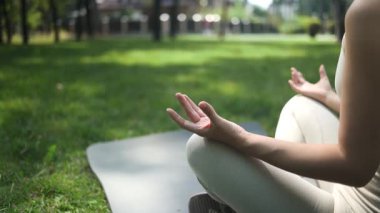 Park yerinde Lotus pozisyonunda meditasyon yapan genç bir kadının yakın çekimi.