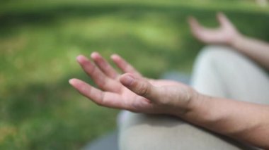 Park yerinde Lotus pozisyonunda meditasyon yapan genç bir kadının yakın çekimi.