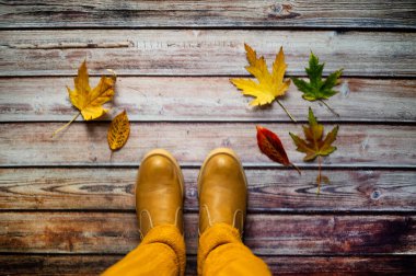 Eski ahşap arka planda renkli yapraklar ve çizmeler. Kopyalama alanı olan üst görünüm.
