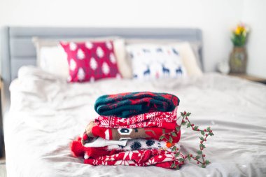 Yatak odasındaki farklı Noel süveterleri yığını. Metin için boşluk.
