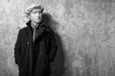 Soyut modern kolaj. David 'in alçıdan kafası olan adam soğuk kış için şık, siyah bir trençkot ve eşarp giymişti.