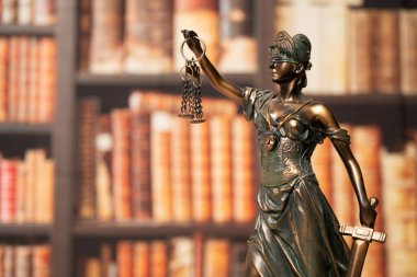 Avukatlık bürosu. Arkaplanı kitaplardan ya da kütüphanelerden oluşan bir duvarla çevrili Adalet Anıtı. Hukuk hukuku, tavsiye ve adalet kavramı