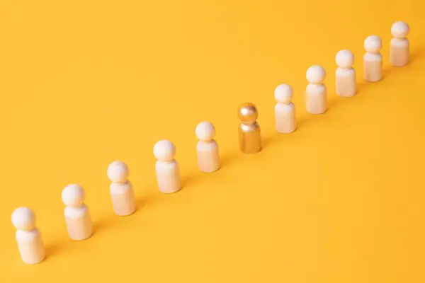 stock image An employee figurine comes out of a row of colleagues. Promotion at work, appointment to the role of team leader. Dismissal of an employee. Take the first step, be different. Initiative and aspiration