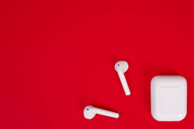 Tokyo, Japonya - Haziran 05, 2022: Apple AirPods kablosuz bluetooth kulaklıklar ve Apple iPhone için kırmızı arka planda kopyalama alanı olan şarj çantası