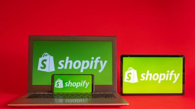 Tokyo, Japonya - Haziran 05, 2022: Shopify web sayfası kırmızı arka planda modern bir dizüstü bilgisayar, akıllı telefon ve not defterinde sergilenmektedir. iPhone üzerindeki logoyu göster