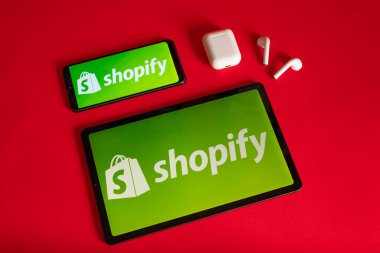 Tokio, Japonya - Haziran 05, 2022: Shopify web sayfası kırmızı arka planda modern bir dizüstü bilgisayar, akıllı telefon ve not defterinde sergilenmektedir. iPhone üzerindeki logoyu göster