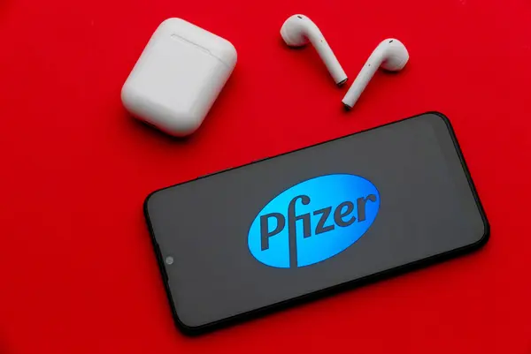 stock image Tula, Russia - Jan 10, 2022: Pfizer logo on smartphone screen on red background.