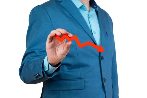 stock image A businessman's hand is holding a red arrow down on a white background. The concept of reducing costs and profits, falling living standards and prices. Decreased projections, depressed economies.