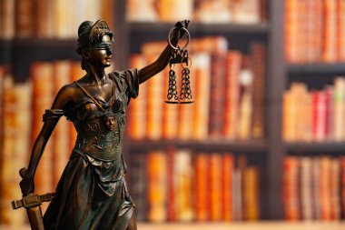 Avukatlık bürosu. Arkaplanı kitaplardan ya da kütüphanelerden oluşan bir duvarla çevrili Adalet Anıtı. Hukuk hukuku, tavsiye ve adalet kavramı