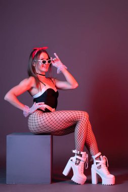 Arka planda poz veren genç ve güzel bir gogo dansçısı kadın..