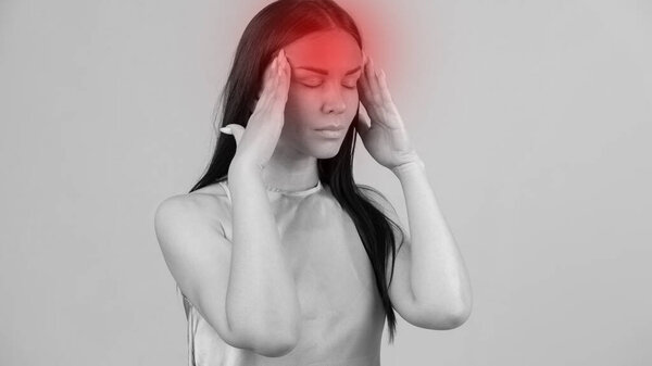 Young beautiful woman has headache, isolated on gray background. Exhausted girl portrait