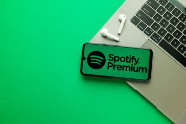 Kyoto Şehri, Japonya - 31 Temmuz 2023: Modern dizüstü bilgisayarın yanındaki akıllı telefondan yeşil arka planda logo Spotify