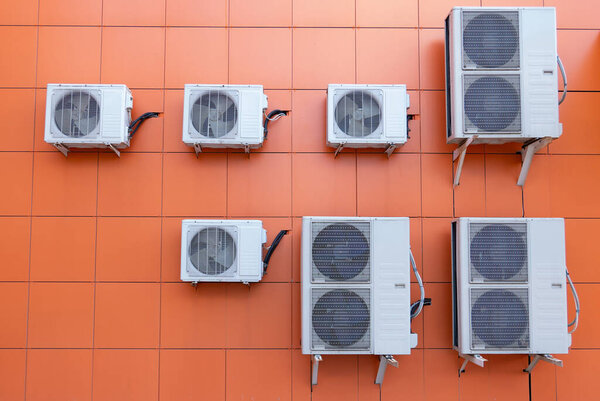 Компрессор кондиционера установлен на открытом воздухе оранжевая стена