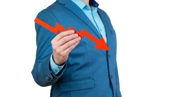 stock image A businessman's hand is holding a red arrow down on a white background. The concept of reducing costs and profits, falling living standards and prices. Decreased projections, depressed economies.