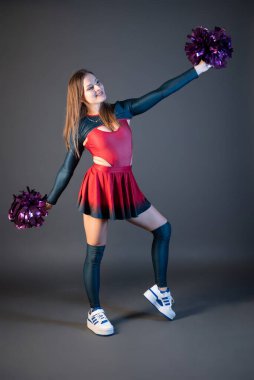 Üniformalı mutlu ponpon kız gri arka planda yalnız dans ediyor.