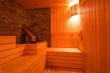 Sauna odasında otur. Taş ısıtıcılı boş ahşap buhar odası. Sağlıklı olmak için sauna odası. Sauna odası ve geleneksel sauna aksesuarları. Sağlıklı ve spa tarzı..