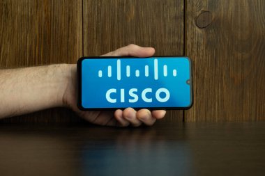 Kyoto Şehri, Japonya - 31 Temmuz 2023: Akıllı telefon ekranındaki Cisco logosu ahşap masa arkasındaki Apple Macbook klavyesine yerleştirildi.