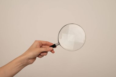 Gri arka planda büyüteç tutan kadın, yakın plan. Anahtar sözcük kavramını bul