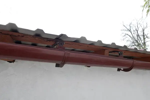 stock image Gutter system for a metal roof. Holder gutter drainage system on the roof.