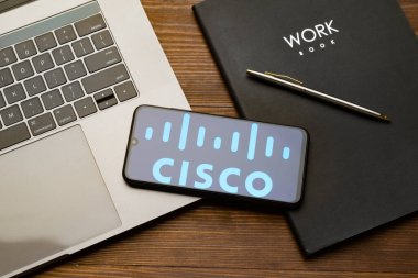 Kyoto Şehri, Japonya - 31 Temmuz 2023: Akıllı telefon ekranındaki Cisco logosu ahşap masa arkasındaki Apple Macbook klavyesine yerleştirildi.