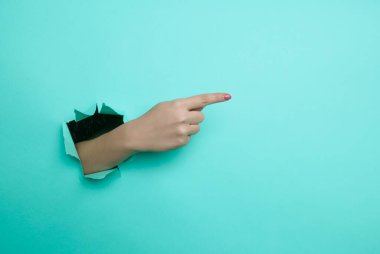 Kadın eli uzayı yakından kopyalamak için işaret ediyor. Yırtık kağıt, mavi arkaplan.