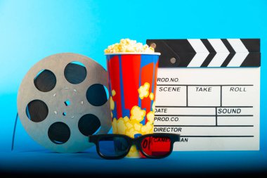 Film alkışı, patlamış mısır, 3D gözlükler ve mavi arka planda film makarası. Kolaj tasarımı