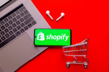Kyoto Şehri, Japonya - 31 Temmuz 2023: Kırmızı arka planda Shopify logosu olan Apple iPhone