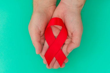 Sağlık ve Tıp Konsepti - erkek elleri kırmızı AIDS farkındalığı kurdelesini tutuyor