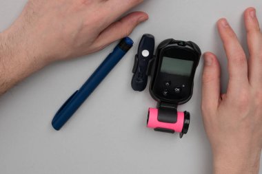 A diabetic man prepares to take a blood test to find out his sugar level. clipart