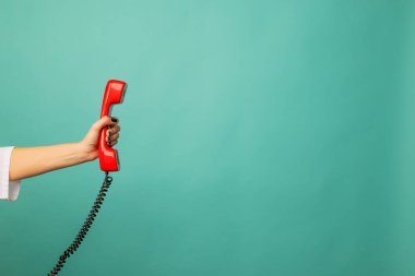 Mavi arka planda kırmızı kablosuz telefonu olan bir kadının yakın görüntüsü, mesaj için yer var. Yardım hattı kavramı