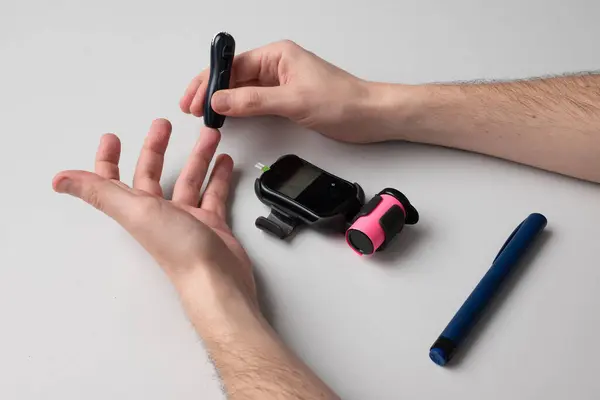 stock image A diabetic man pricks his finger with a lancet to find out the sugar level.