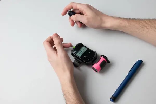 stock image A man with diabetes is tested with a glucometer to find out his blood sugar level.