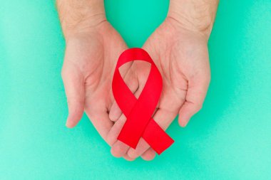 Sağlık ve Tıp Konsepti - erkek elleri kırmızı AIDS farkındalığı kurdelesini tutuyor