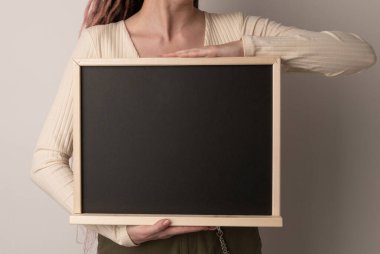 Güzel bir kadın beyaz arka planda tebeşir tahtası tutuyor.