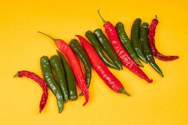 Красный и зеленый острый перец чили на желтом фоне